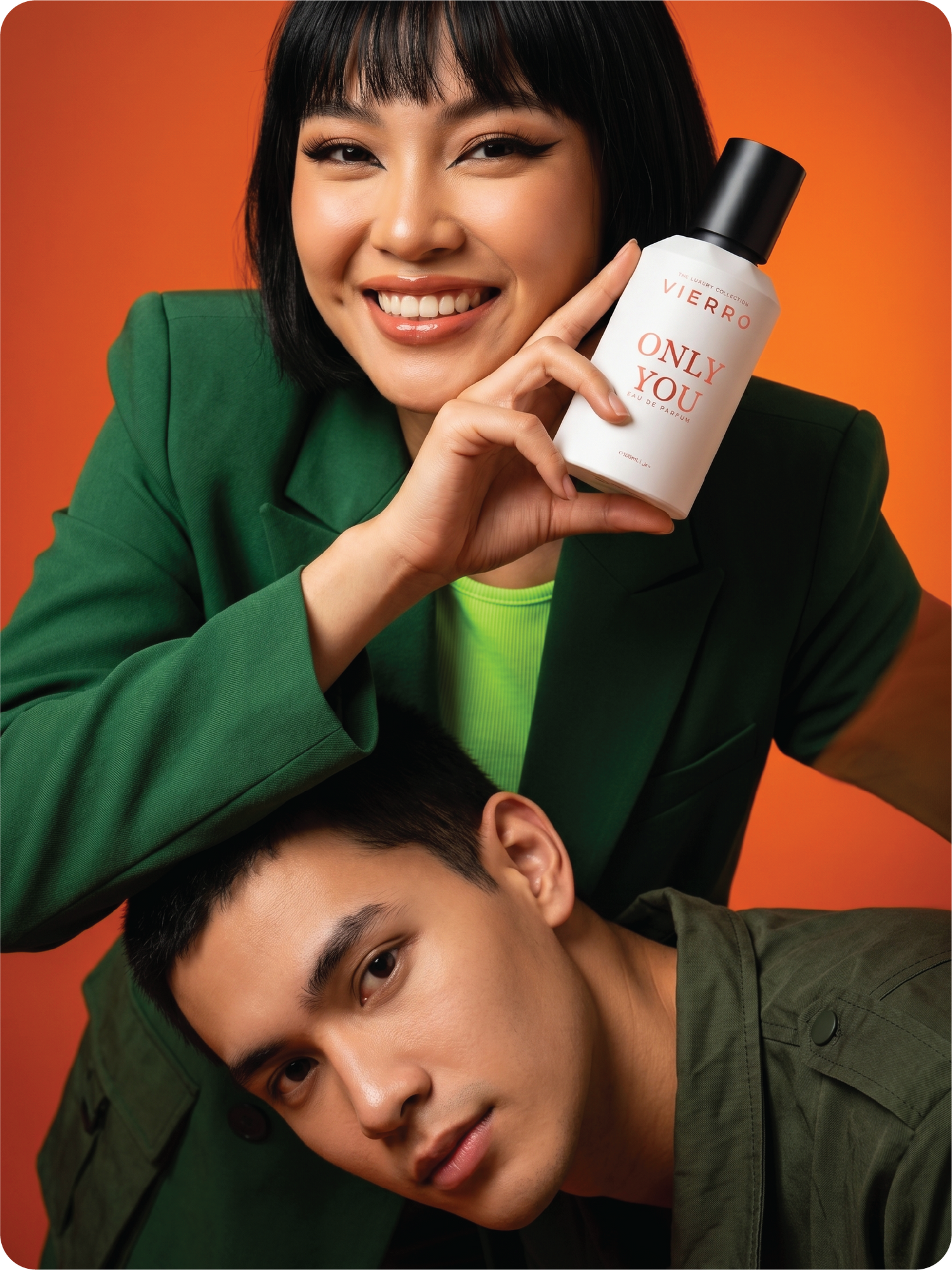 Person holding a bottle labeled 'Vierro Only You luxury perfume' with another person underneath on an orange background