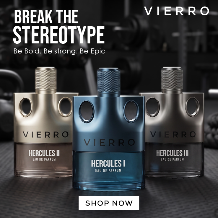 Three VIERRO perfume bottles are displayed against a dark, blurred industrial background. The center bottle is metallic blue and labeled HERCULES I, while the bottles on the left and right are metallic silver and labeled HERCULES II and HERCULES III respectively.
