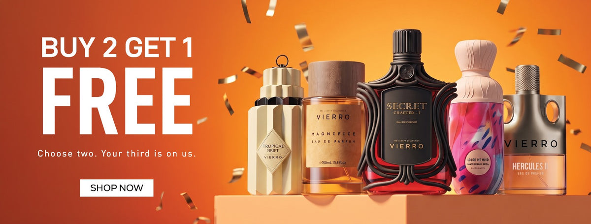 A promotional banner for a "Buy 2 Get 1 Free" sale featuring five Vierro perfume bottles—including Tropical Oud, Nabd Al Rimal, Secret, a floral bottle, and Hercules—displayed on an orange podium against a warm, glowing orange background with confetti and a "Shop Now" button.